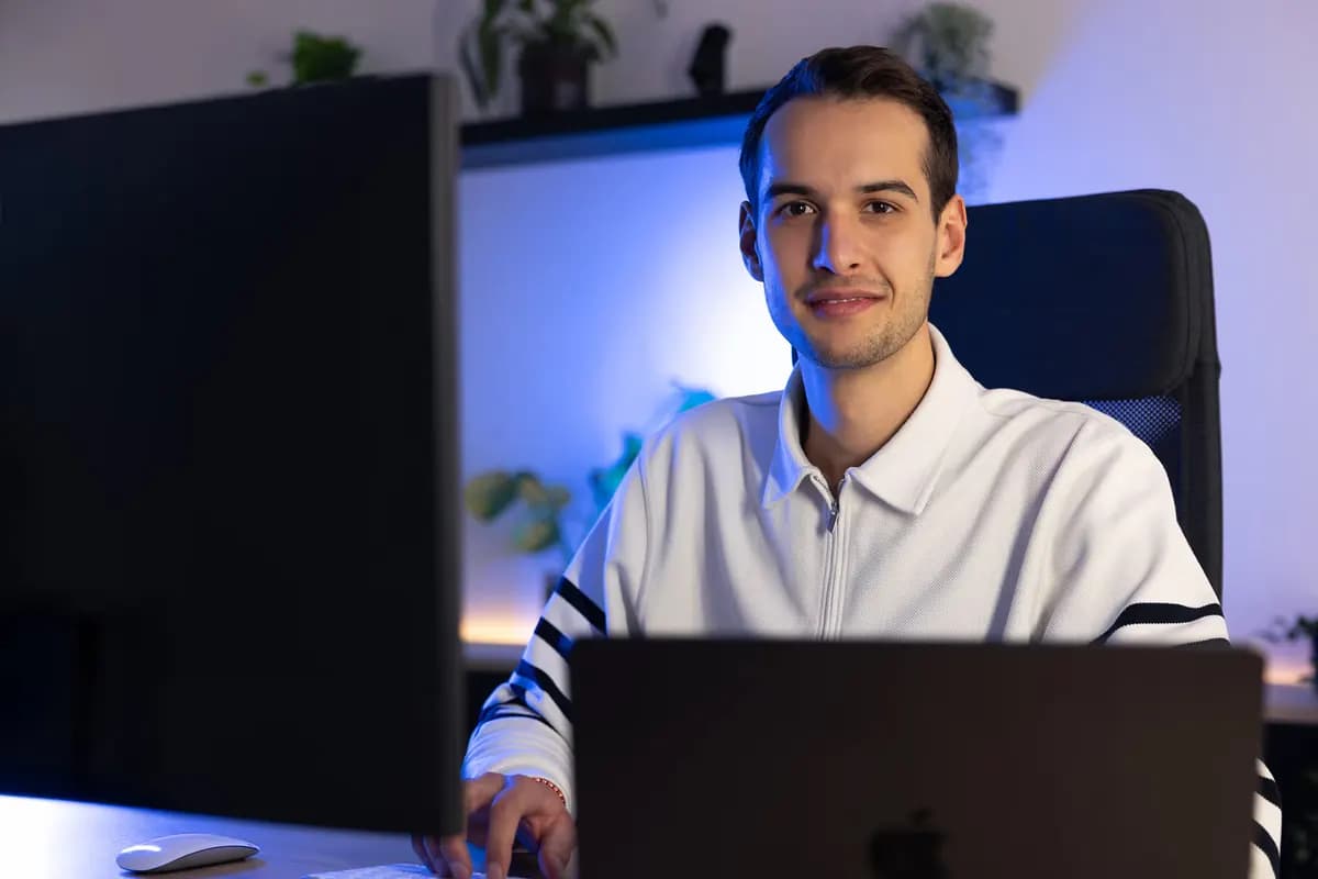 Ein Mann arbeitet an einem Laptop und einem Bildschirm.